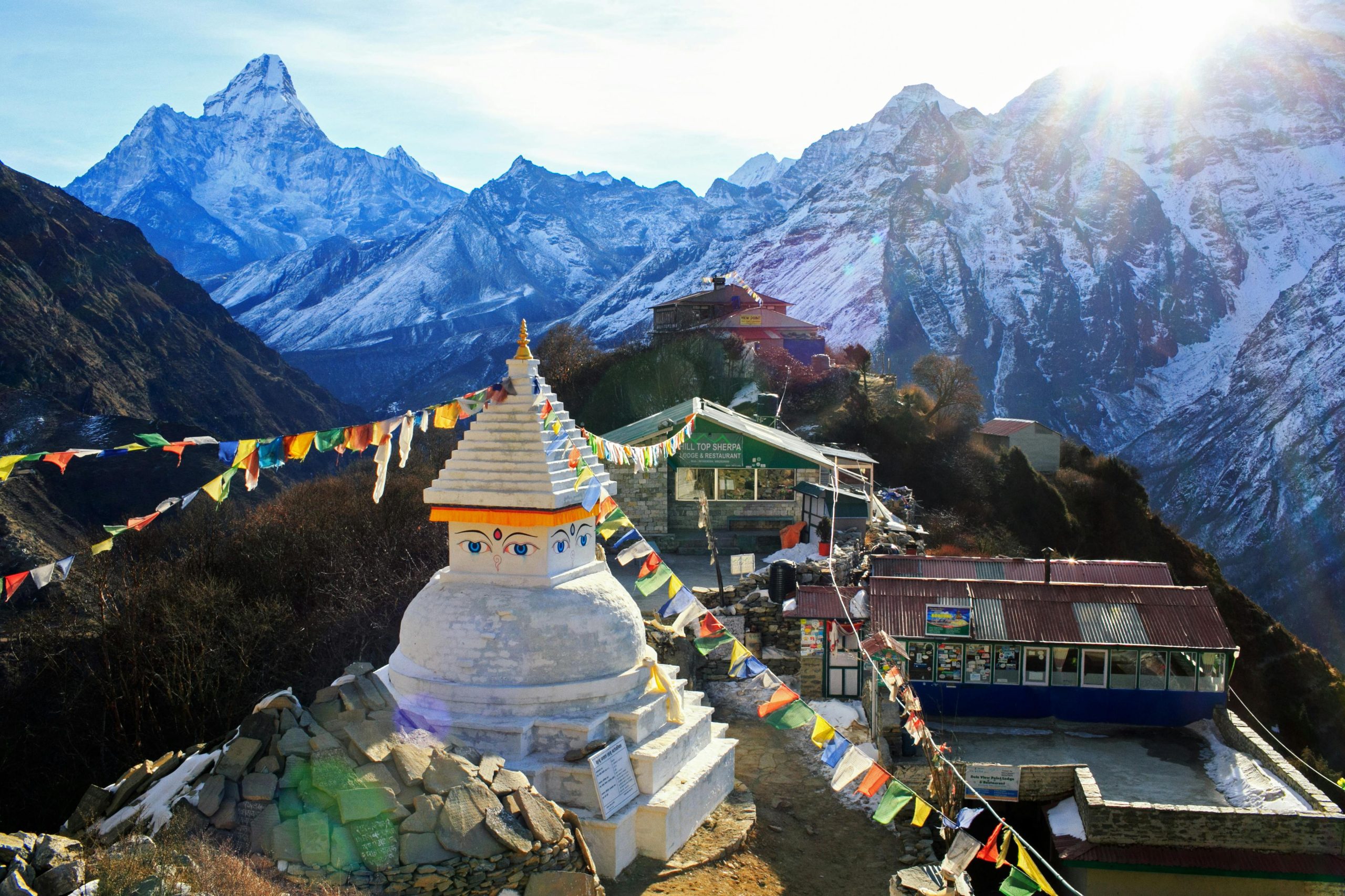 Aerial view of a Sherpa village in the Everest region of Nepal, surrounded by Himalayan mountains and clouds, popular stop on Everest trekking routes.