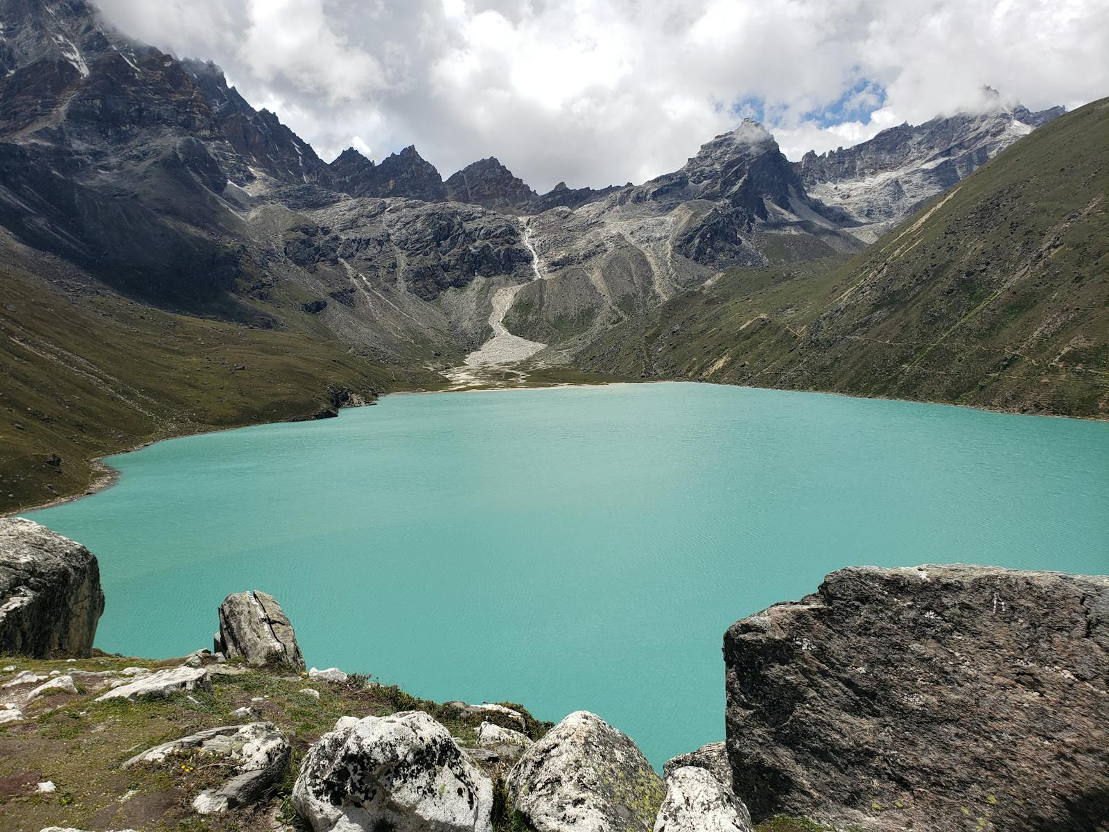 Serene view of Gokyo Lake with surrounding majestic mountains in Sagarmatha National Park, Nepal.